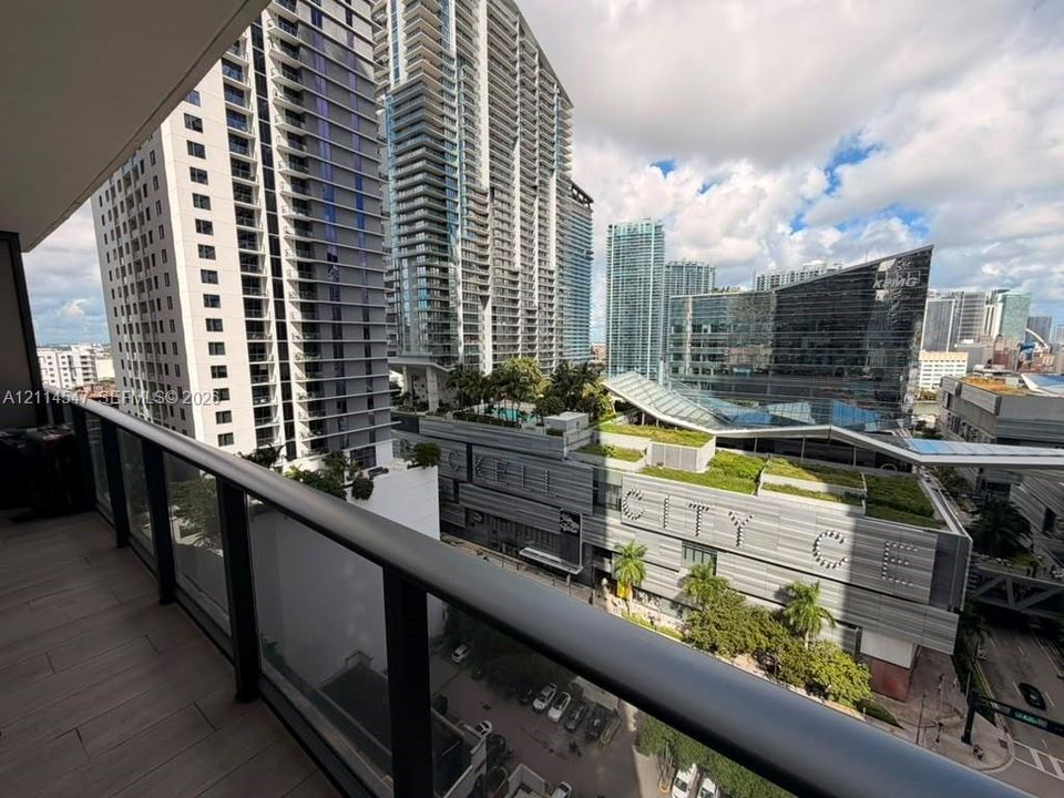Covered balcony featuring wood-finish tile flooring and a glass-paneled railing