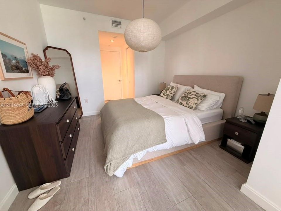Interior room featuring neutral-toned wood-finish flooring, a textured globe pendant light fixture, and a smooth-finish white ceiling