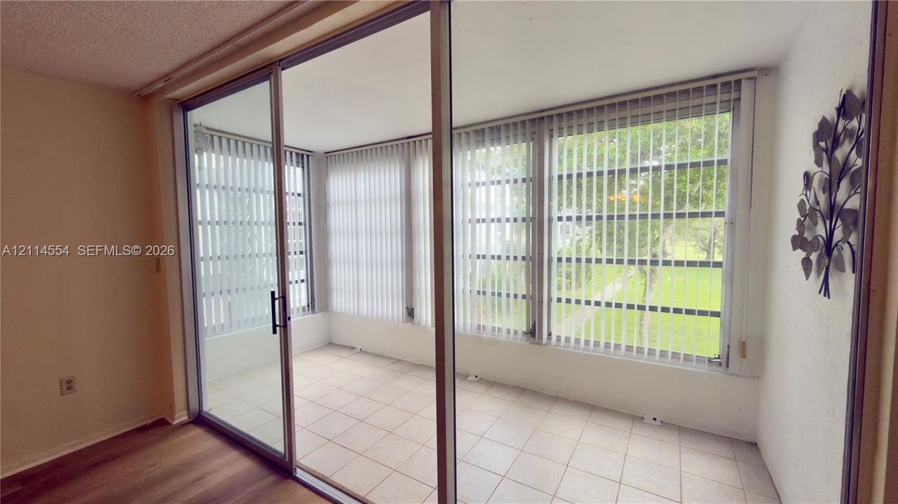 Enclosed sunroom featuring floor-to-ceiling windows, sliding glass panel doors, and ceramic tile flooring