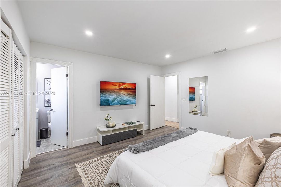 Recessed ceiling lighting, wood-finish flooring, and white louvered closet doors