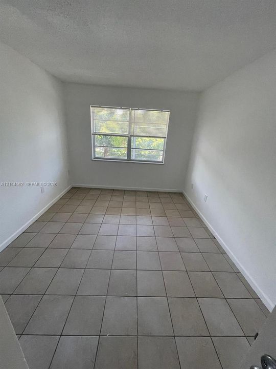 Neutral-toned square ceramic floor tiling, smooth white walls, and a large single-hung window