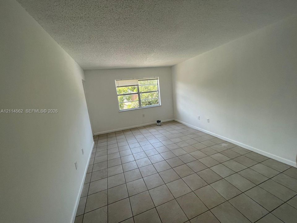 Interior room featuring neutral wall finishes, tile flooring, and a window with horizontal blinds