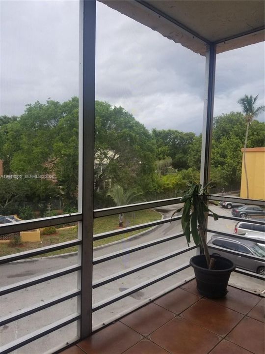 Screened balcony featuring ceramic tile flooring and a metal railing