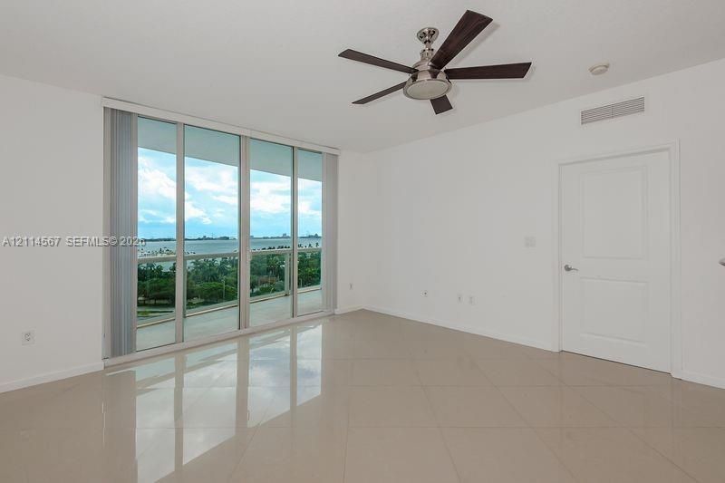 Floor-to-ceiling glass sliders, tile flooring, and a five-blade ceiling fan featuring a brushed nickel finish