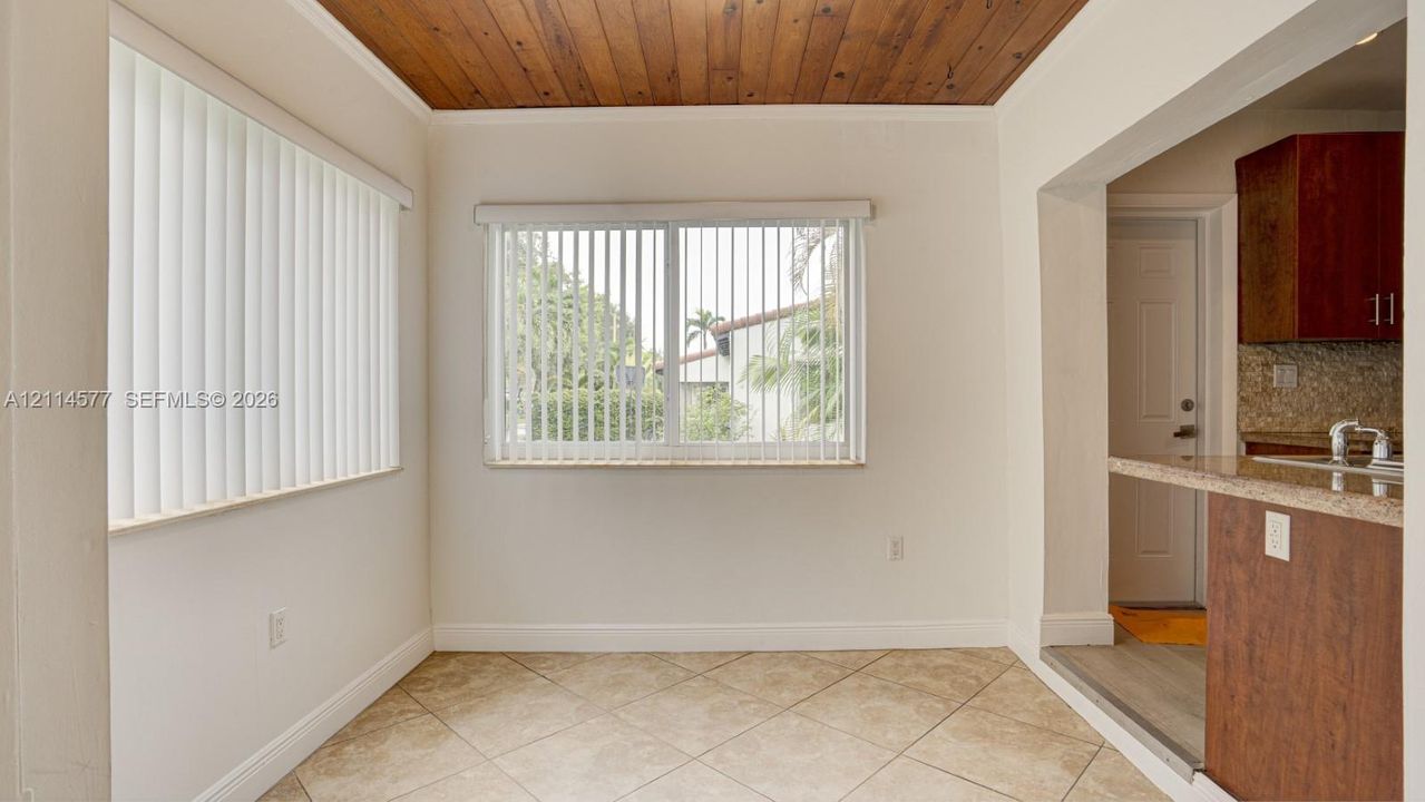 Wood-plank ceiling, neutral tile flooring, and sliding windows with vertical blinds
