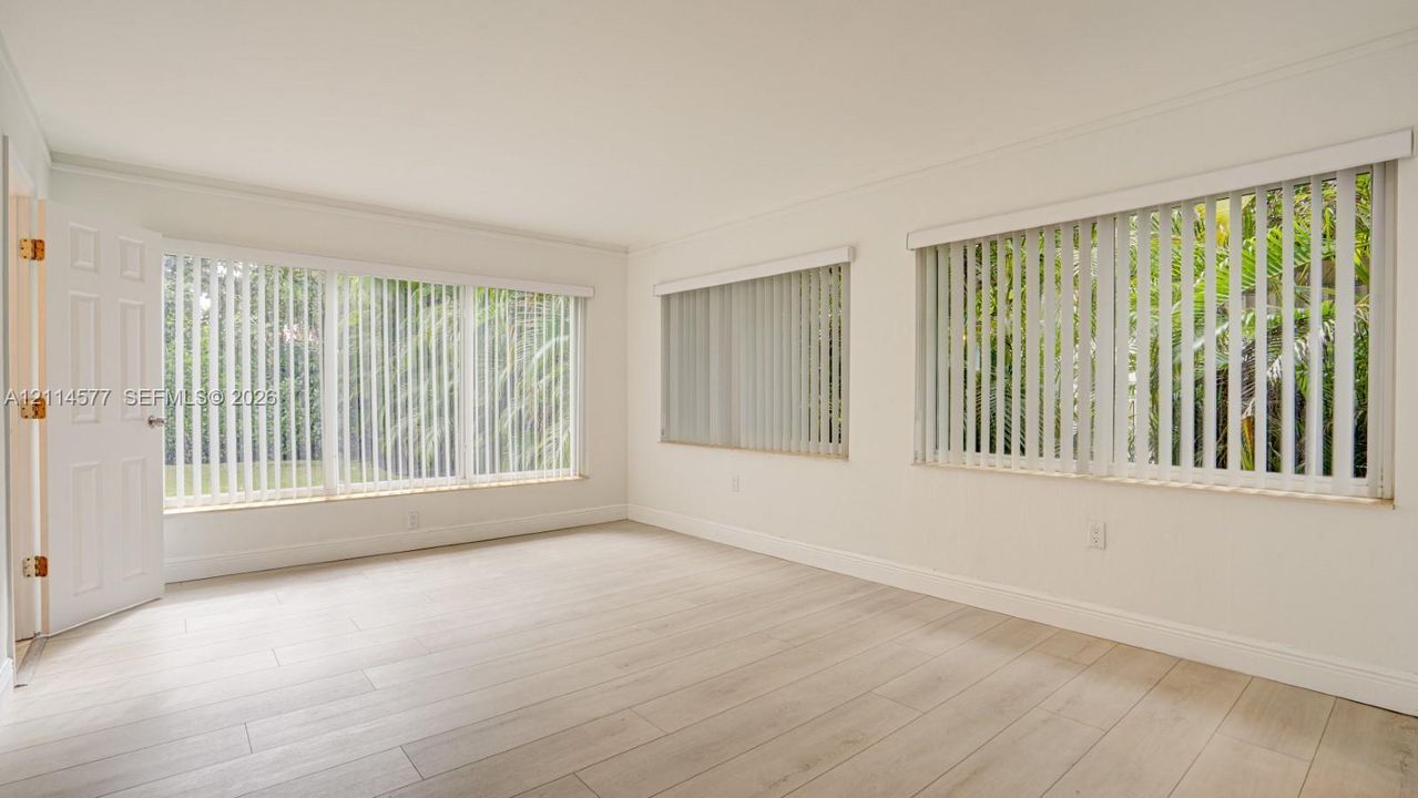 Interior space featuring wood-finish flooring, multi-pane windows with vertical blinds, and a paneled entry door