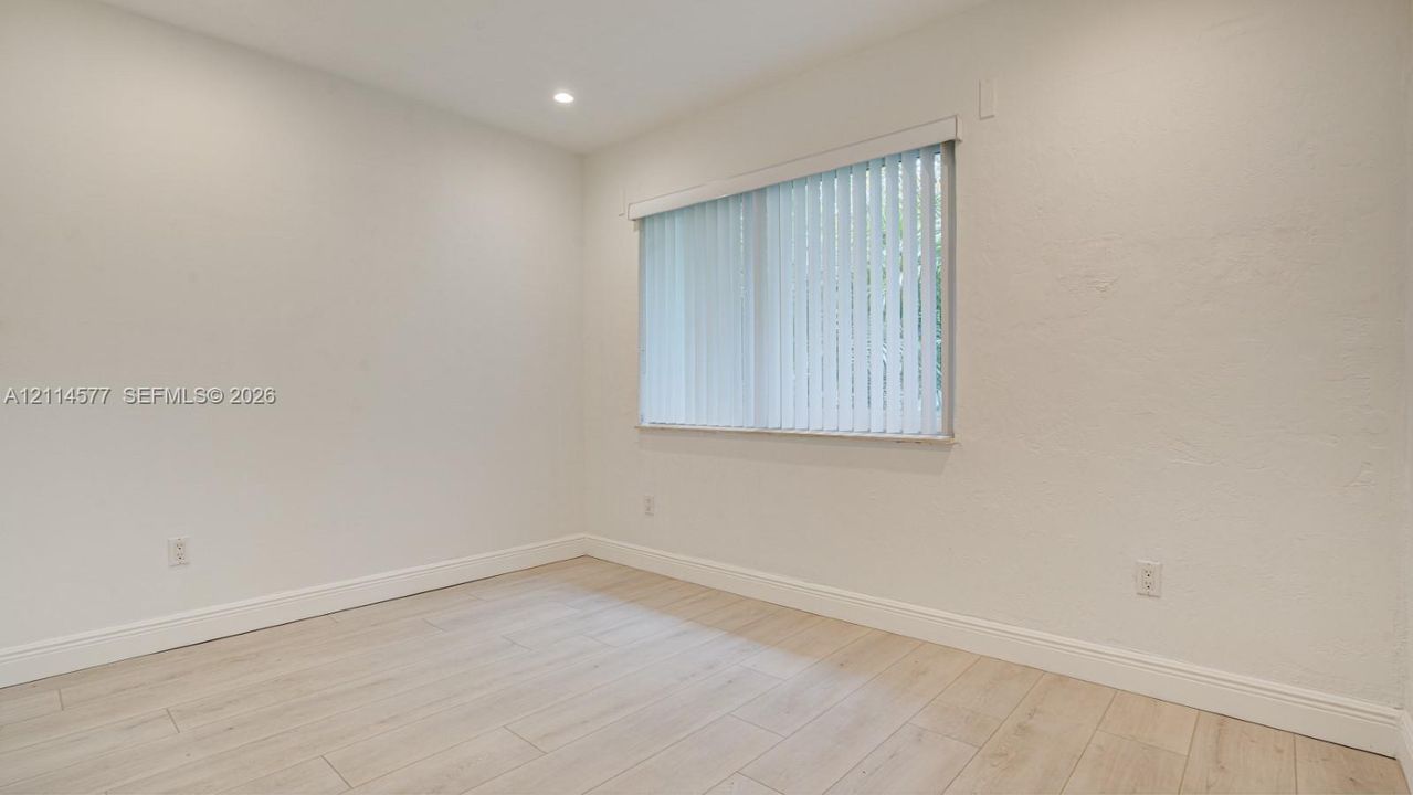 Neutral-toned interior featuring wood-finish flooring, recessed lighting, and vertical window blinds