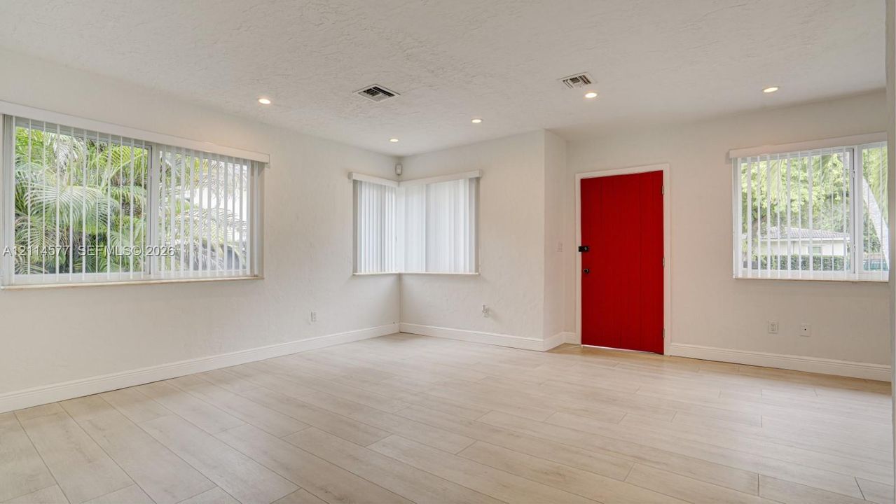 Neutral walls paired with light-toned wood-finish flooring, recessed lighting, and vertical window blinds