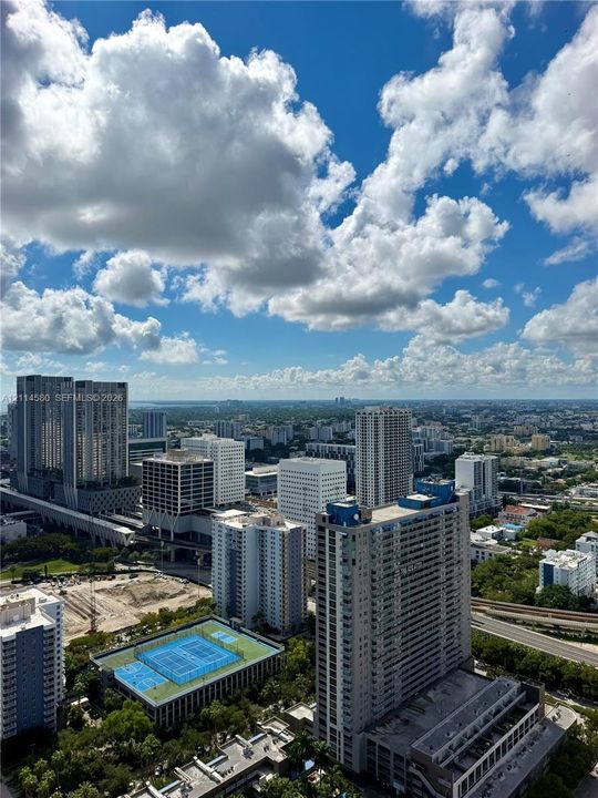Elevated urban outlook featuring a high-rise skyline, cityscape horizon, and a multi-court recreational facility
