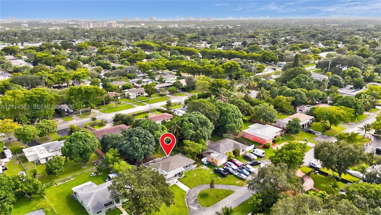 Aerial perspective of a property featuring mature trees and a paved driveway