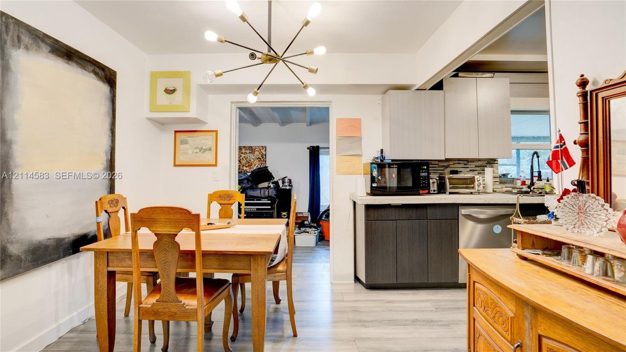 Kitchen featuring flat-panel two-tone cabinetry, wood-finish flooring, and a multi-arm modern light fixture