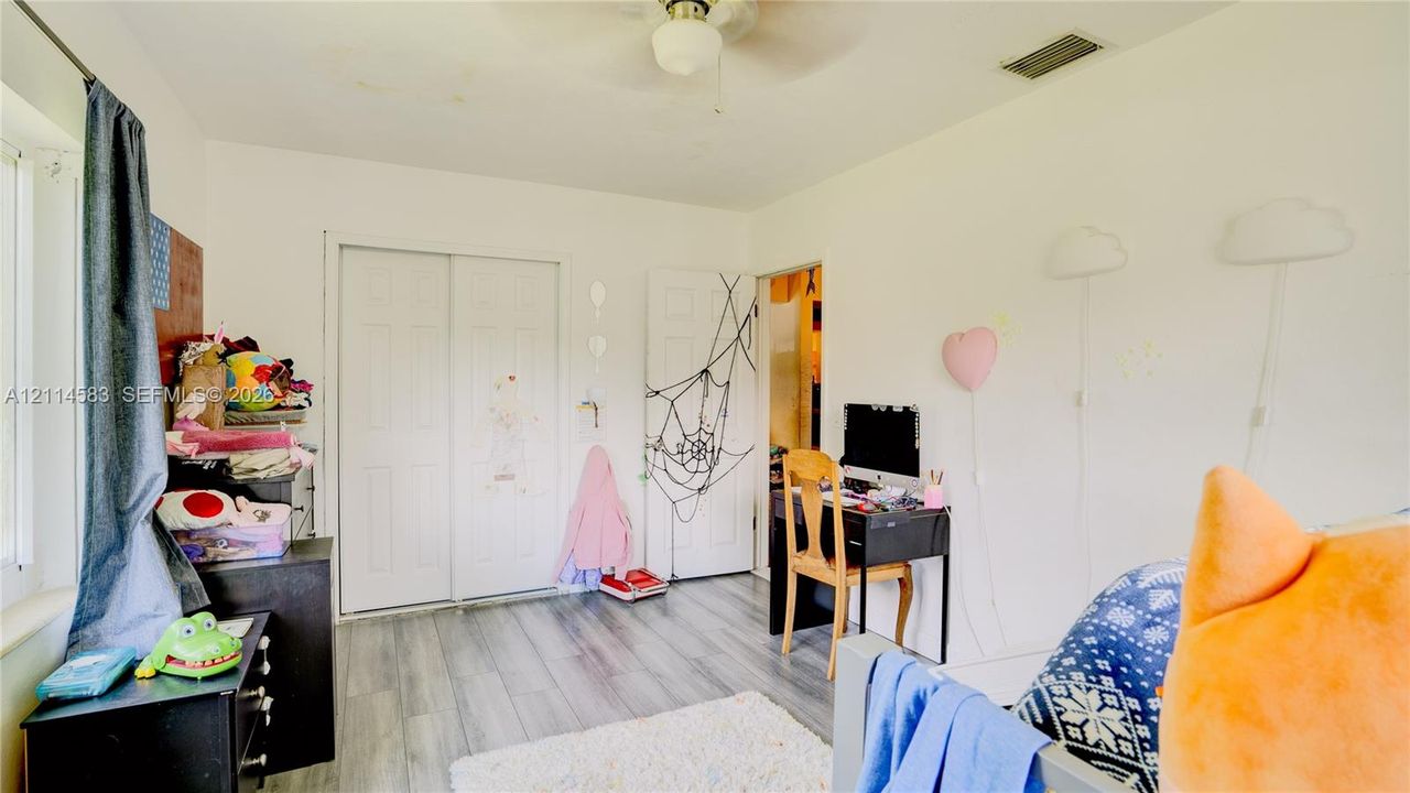 Room featuring wood-finish flooring, a ceiling fan with integrated lighting, and a dual-panel closet