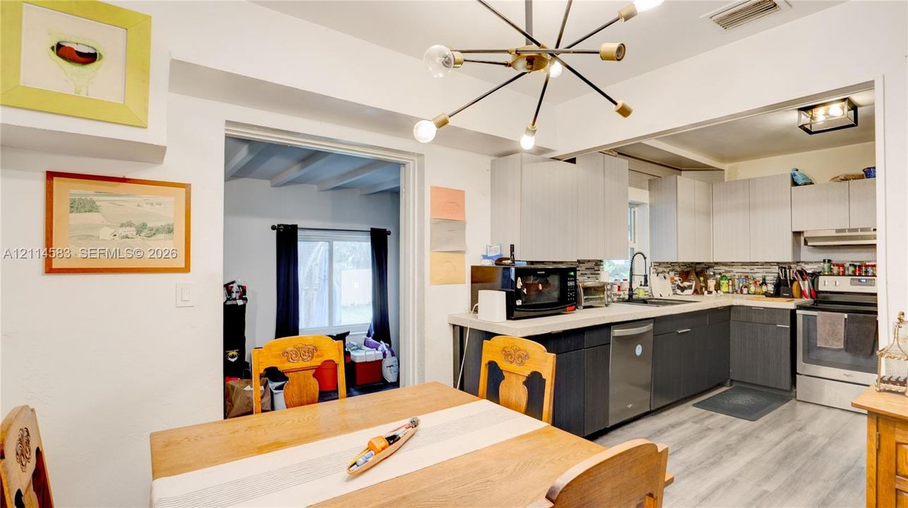 Kitchen featuring two-tone cabinetry, wood-finish flooring, a multi-arm Sputnik-style chandelier, and light-toned solid surface countertops