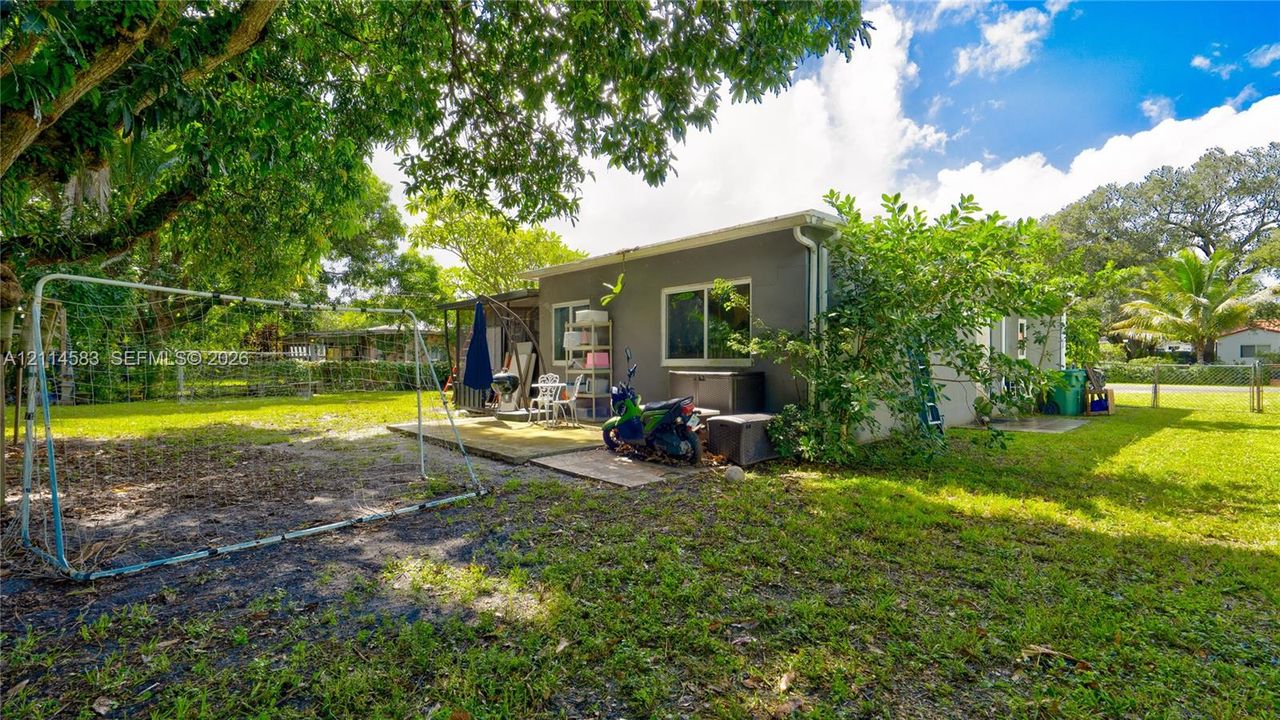 Expansive backyard featuring mature shade trees, a concrete patio, and perimeter fencing