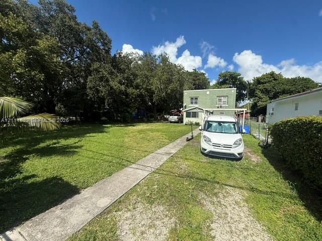 Expansive grass lot featuring mature shade trees and a concrete walkway