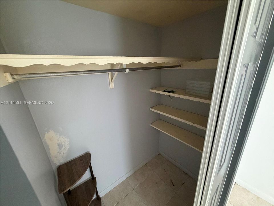 Closet featuring tile flooring, a built-in rod, and multi-tiered shelving