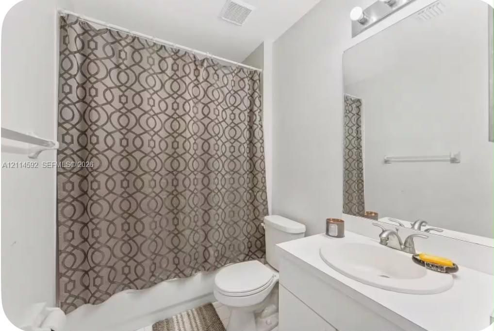 Bathroom featuring a white vanity with an integrated oval sink, chrome faucet, wall-mounted mirror, and a tub-shower combination