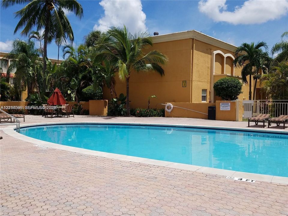 Swimming pool with a brick-paver deck and surrounding palm trees