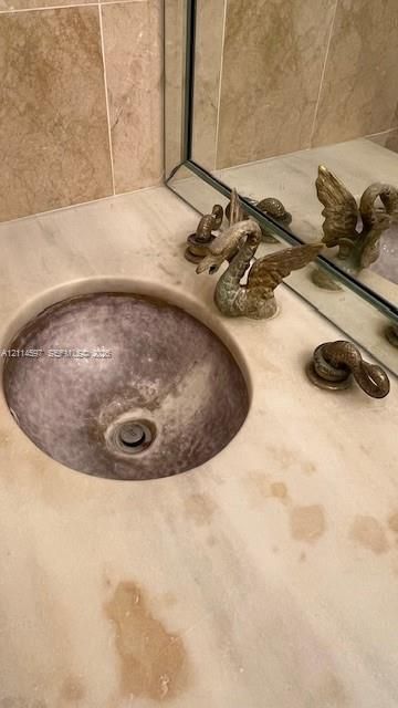 Countertop basin integrated into a stone vanity surface, complemented by decorative swan-motif faucet hardware and a large-format mirrored backsplash