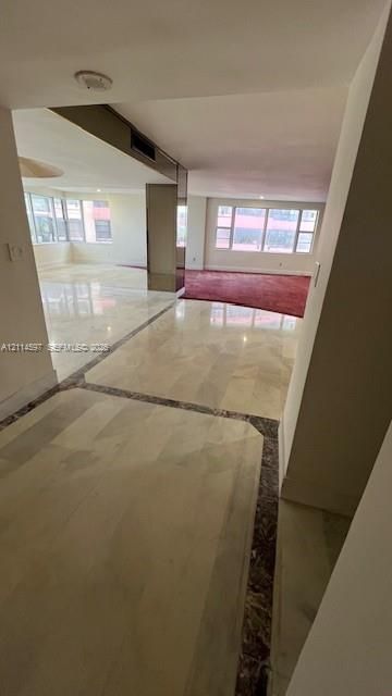Polished stone flooring with decorative inlay borders, expansive windows, and mirrored support columns