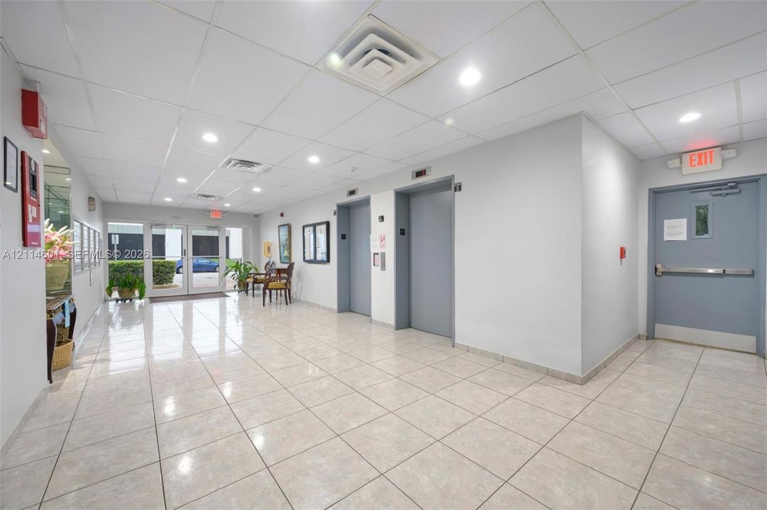 Common area lobby featuring tile flooring, recessed lighting, drop ceiling, and dual elevator access