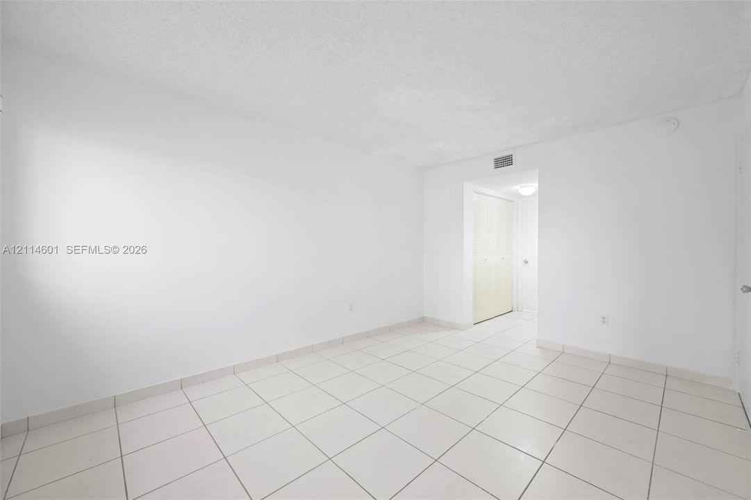 Neutral interior featuring large-format ceramic floor tiling and a built-in closet with bi-fold doors