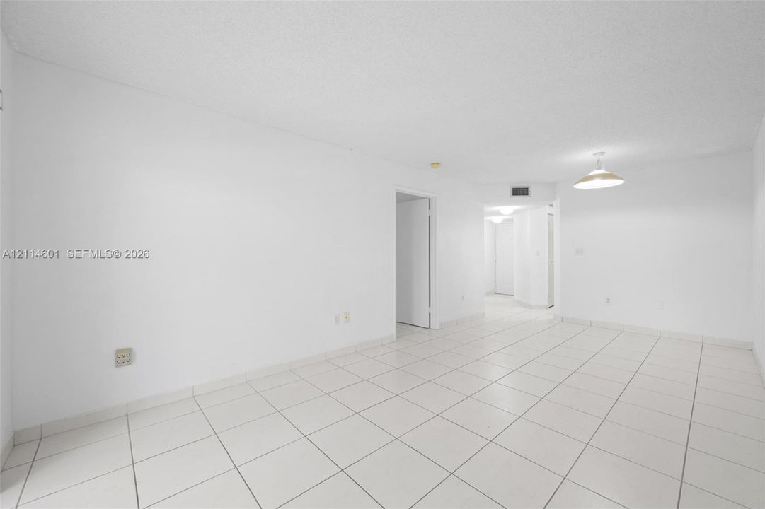 Open interior space featuring light-toned tile flooring, white walls, and a bowl-style pendant light fixture