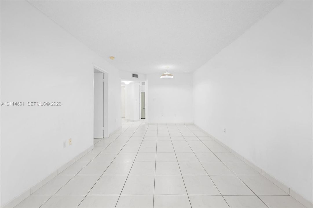 Interior area featuring white walls, neutral tile flooring, and a central pendant light fixture