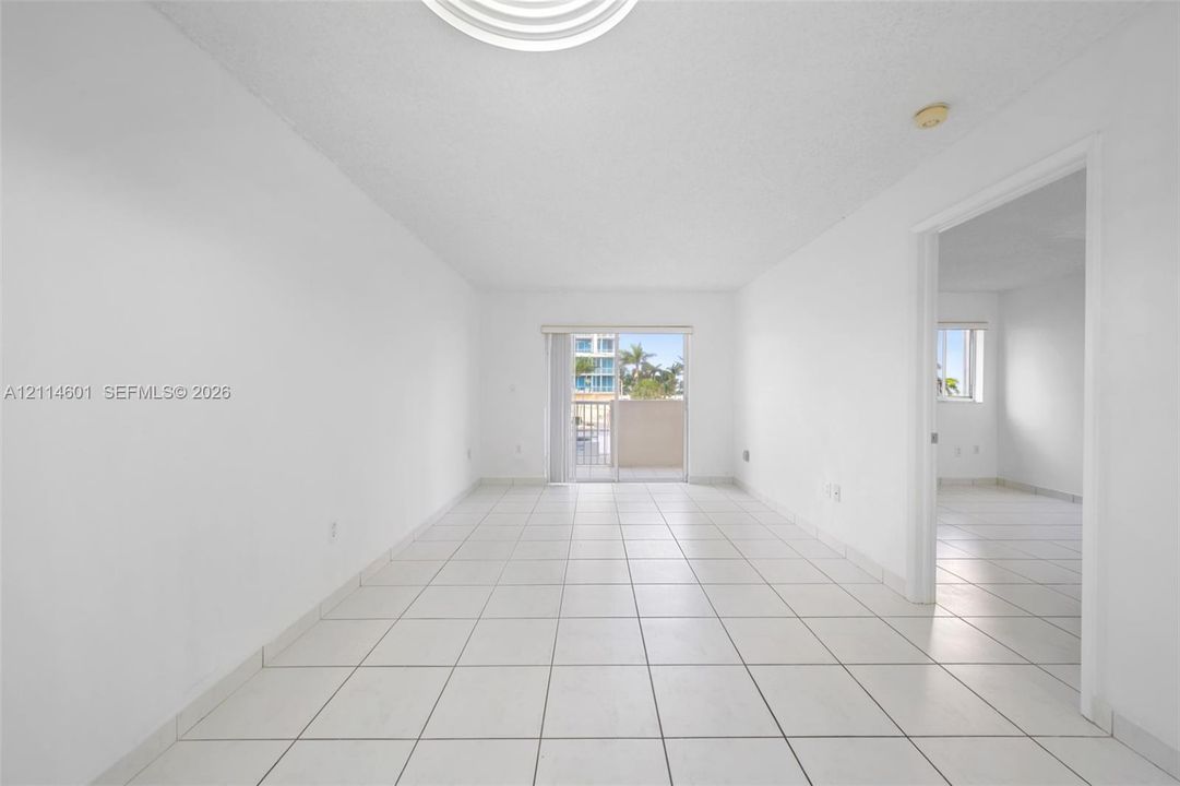 Interior space featuring white ceramic tile flooring, neutral wall finishes, and glass sliding doors leading to an exterior balcony