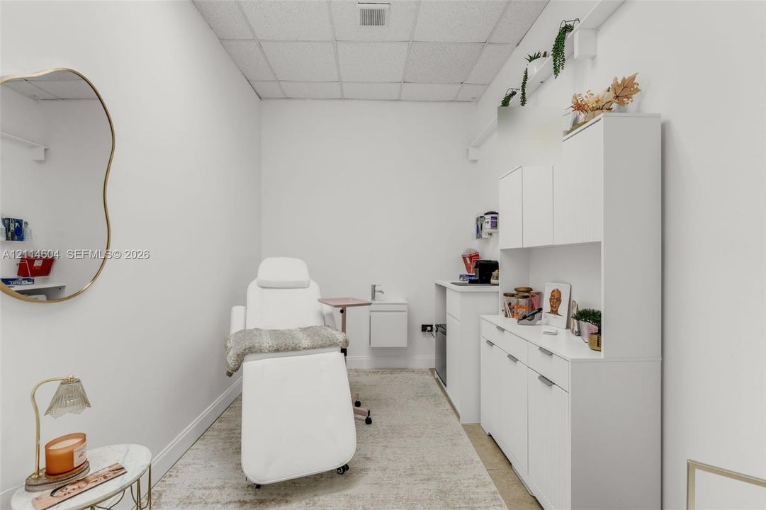 Built-in white cabinetry featuring upper and lower storage, wall-mounted sink with faucet, and minimalist interior design