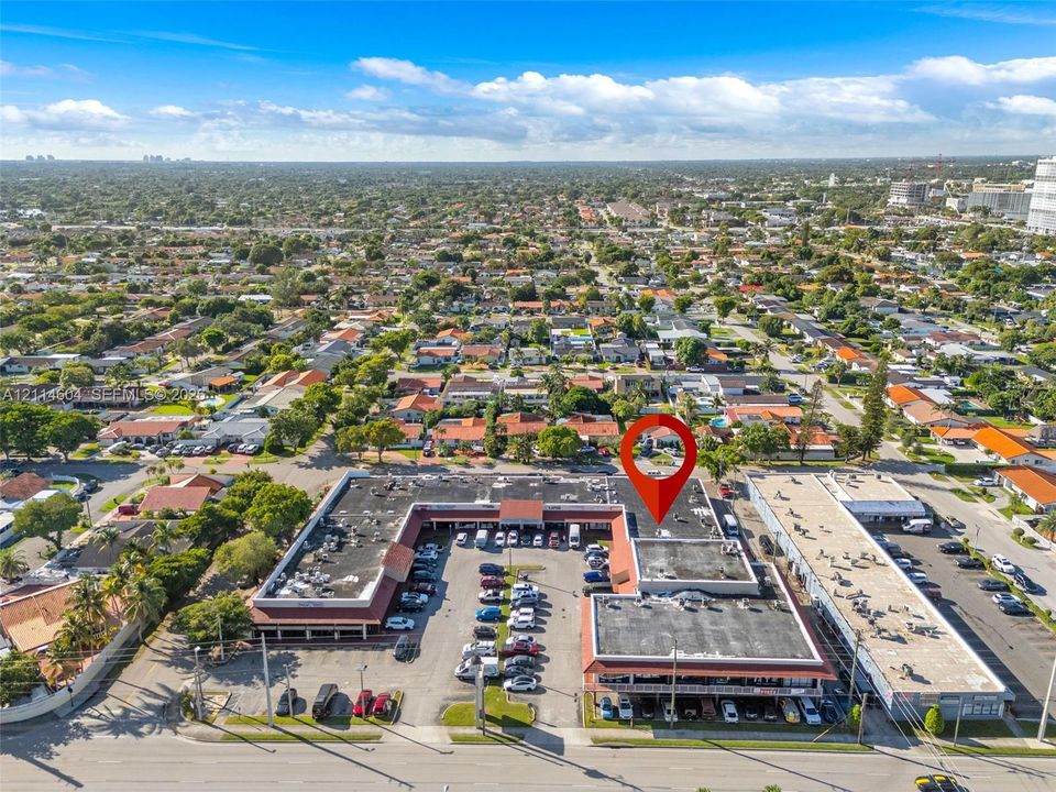 Commercial plaza featuring a U-shaped building configuration, extensive surface parking, and road frontage