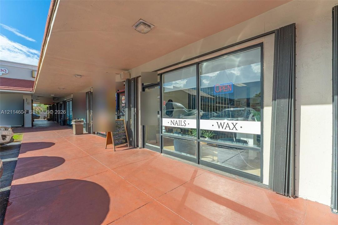 Commercial storefront featuring a full-height glass display window, metal framing, and a covered exterior walkway