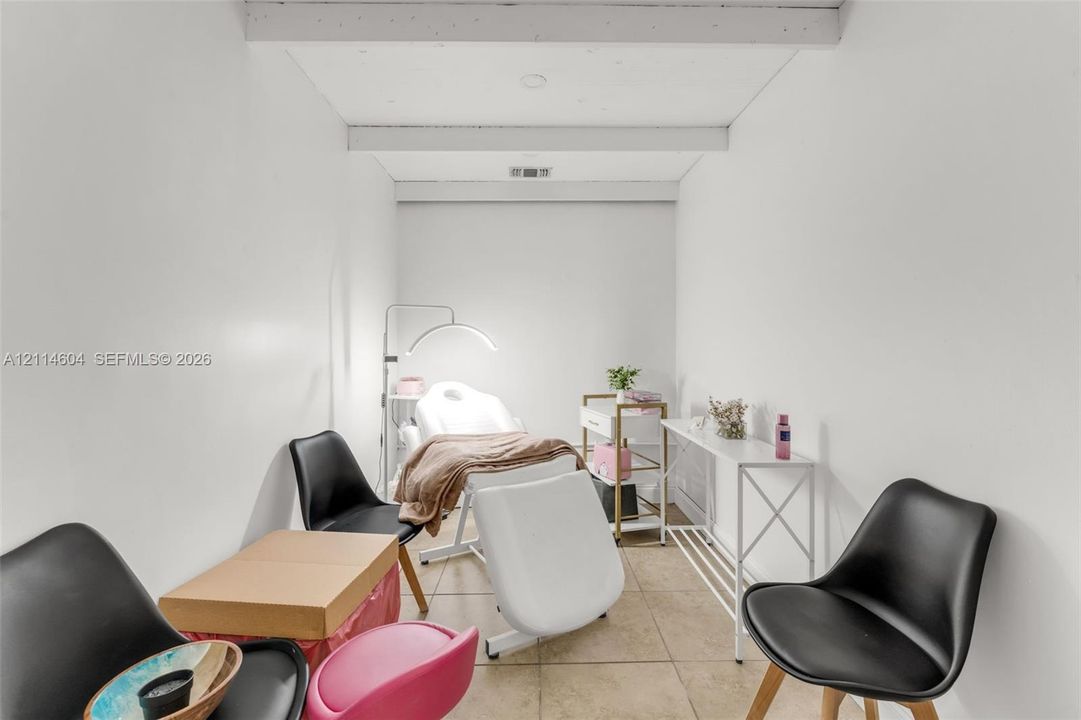 Neutral-toned interior room featuring tile flooring and exposed overhead ceiling beams