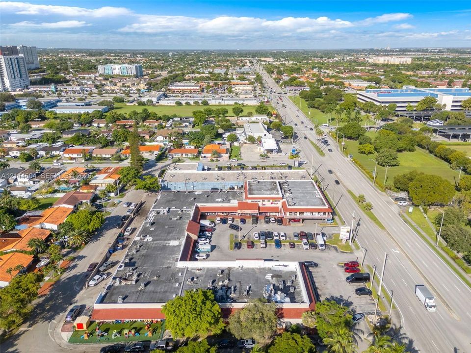 Commercial property featuring a multi-unit layout, flat roof system, and dedicated asphalt parking area situated on a high-traffic roadway