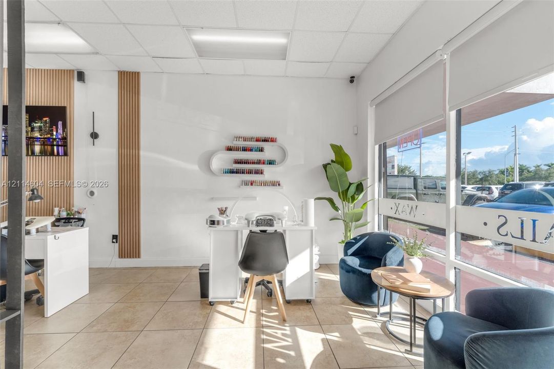 Interior space featuring floor-to-ceiling glass storefront windows, neutral tile flooring, decorative vertical wood-slat wall accents, and a suspended drop ceiling