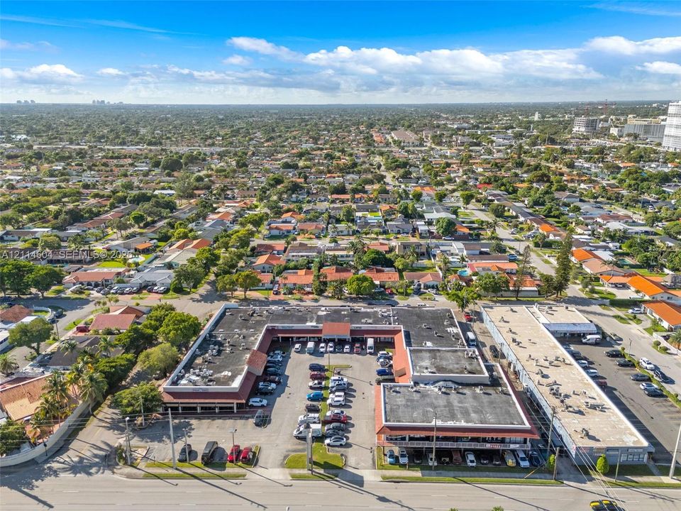 U-shaped commercial structure featuring a central asphalt parking lot, paved perimeter access, and high-visibility road frontage
