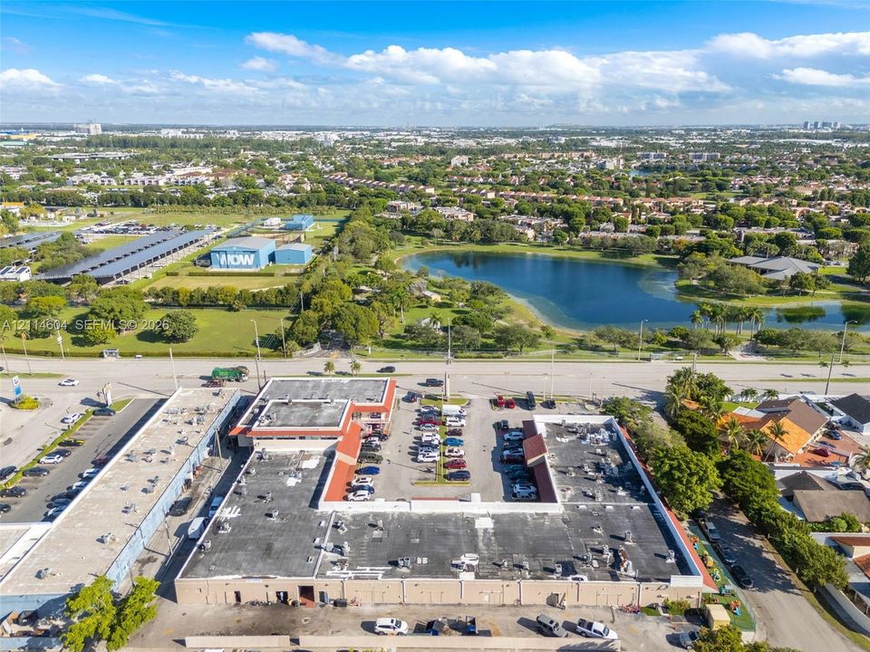 Commercial property featuring a sprawling U-shaped building, extensive asphalt-paved parking areas, and a concrete exterior