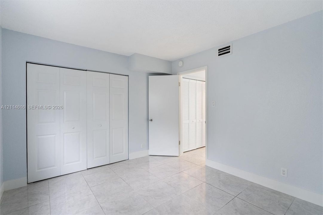 Interior space featuring neutral wall tones, large-format tile flooring, and integrated white bi-fold closet doors