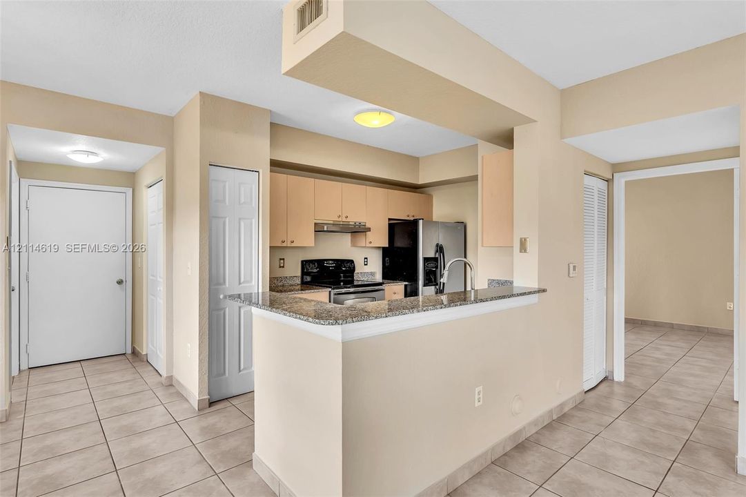 Kitchen featuring wood cabinetry, stone countertops, a breakfast bar, and stainless steel appliances