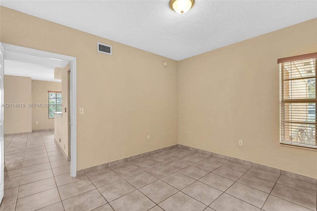 Neutral-toned interior space featuring light tile flooring, a window equipped with horizontal slat blinds, and a dome-style ceiling light fixture