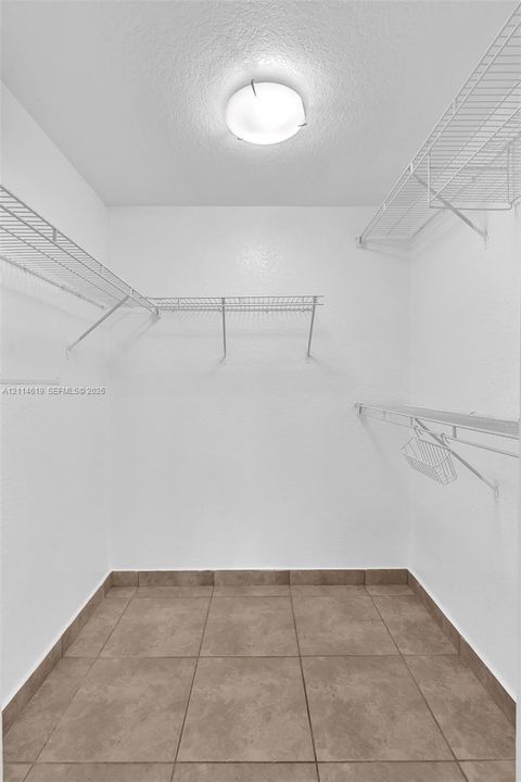Storage space featuring tiered wire shelving and large-format tile flooring, illuminated by a ceiling-mounted light fixture
