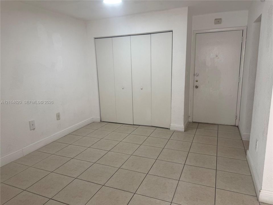Neutral-toned ceramic tile flooring, four-panel closet with white doors, and a solid-panel entry door