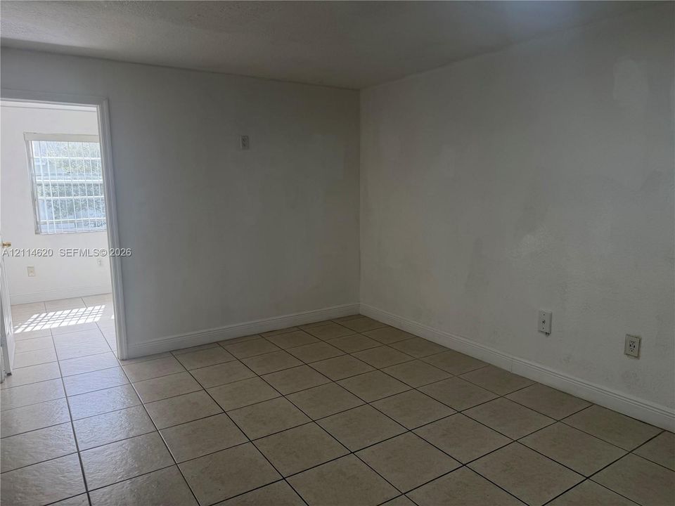 Interior space featuring neutral wall finishes, tile flooring, and a window with security bars