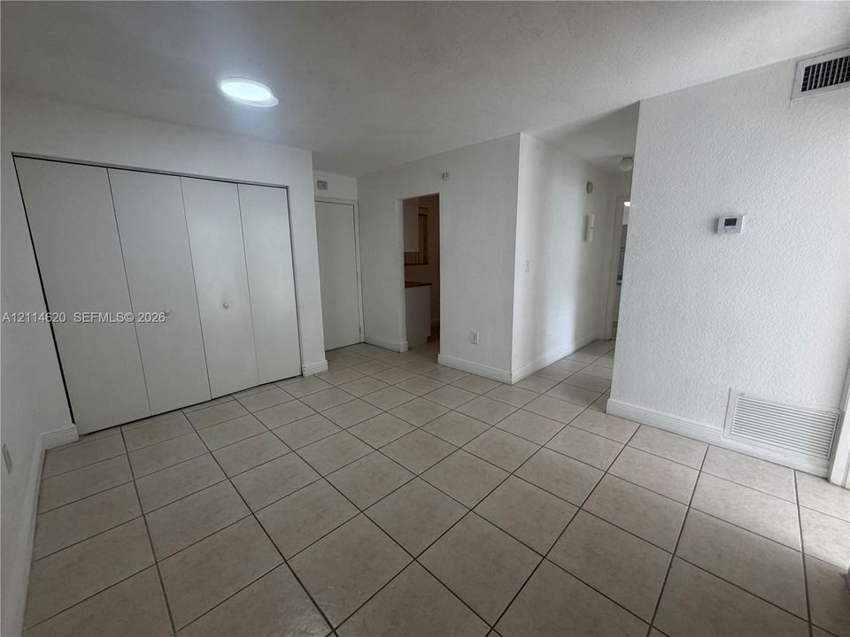 Neutral tile flooring, ceiling-mounted lighting, and expansive wall-to-wall closet storage with folding doors