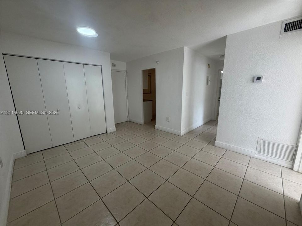 Neutral-toned ceramic tile flooring, built-in closet with multi-panel sliding doors, and ceiling-mounted flush lighting