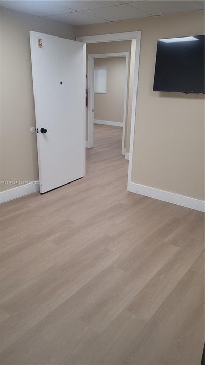 Interior space featuring neutral wall paint, wood-finish flooring, and white door trim
