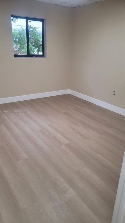 Neutral wall finishes, wood-finish flooring, and single-pane window with dark frame