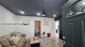 Interior entry featuring a dark-toned door with an arched glass insert, wood-finish flooring, recessed lighting, and a contrasting dark ceiling