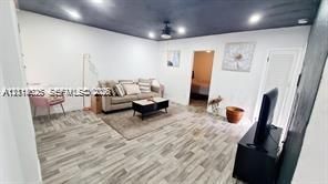 Neutral interior space featuring wood-finish flooring, a dark-toned ceiling, and recessed lighting