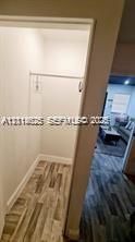 Reach-in closet featuring wood-finish flooring and a built-in metal hanging rod